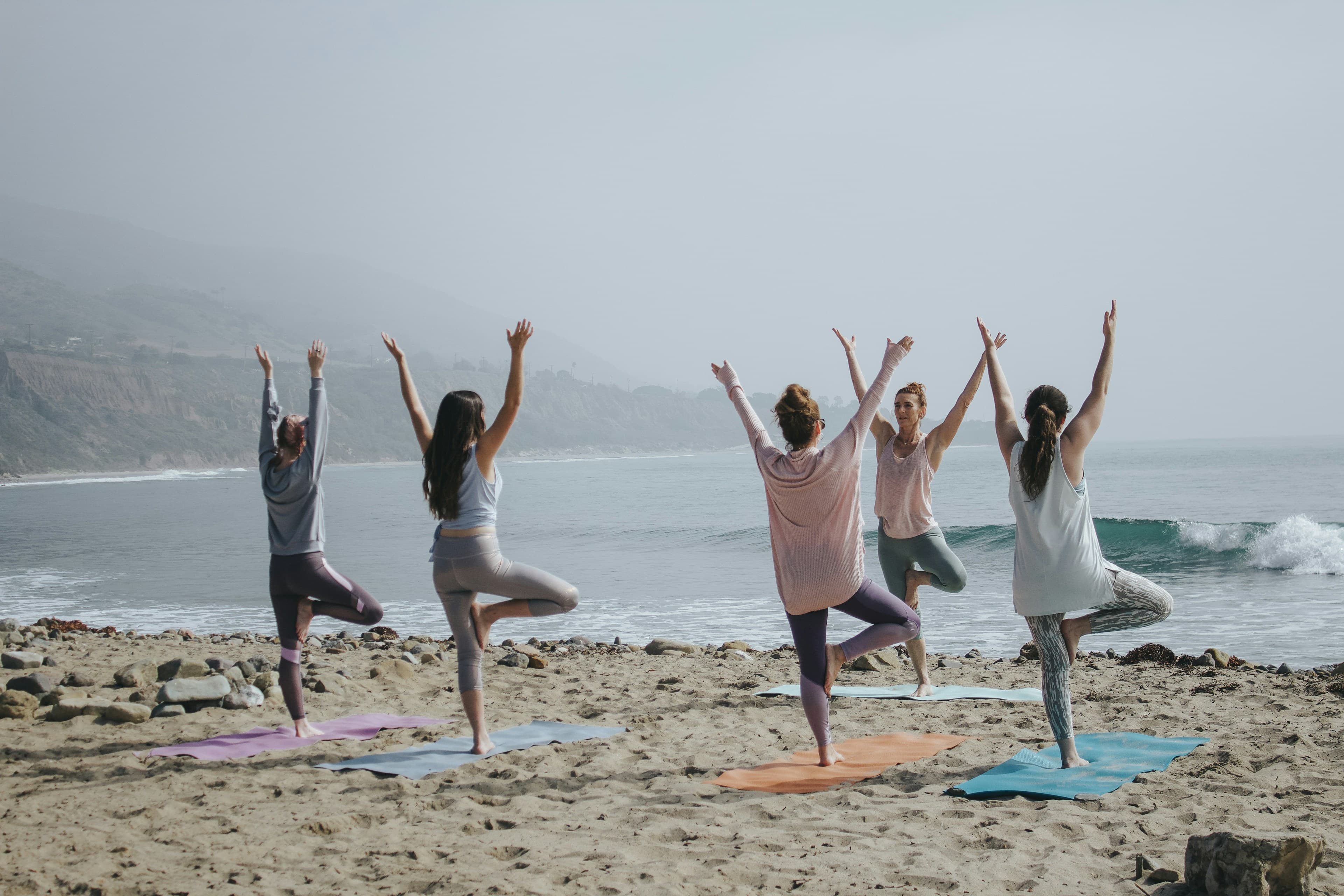 A group practising yoga on a beach