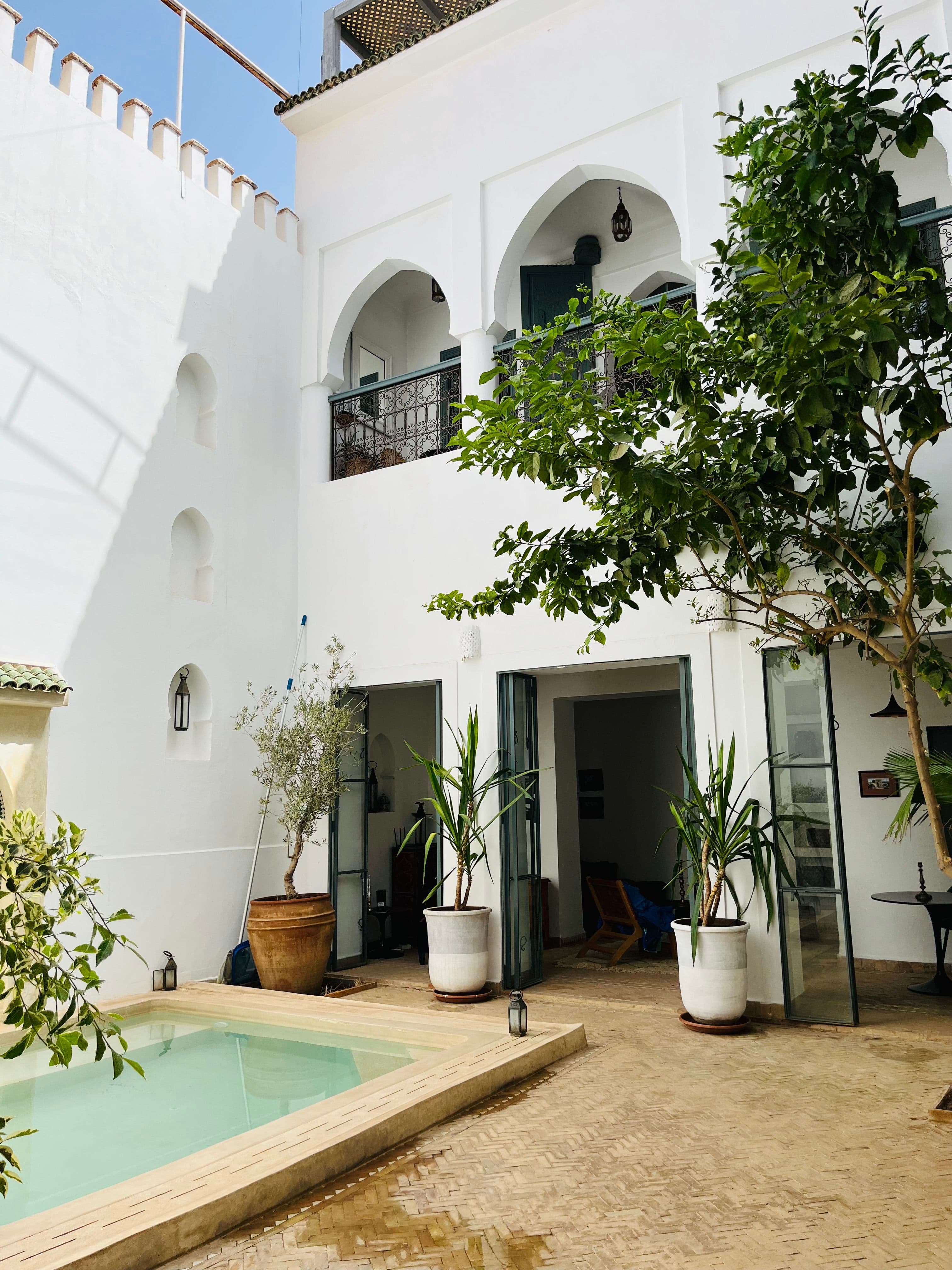 A refined Marrakech riad courtyard with white arches and a quiet pool