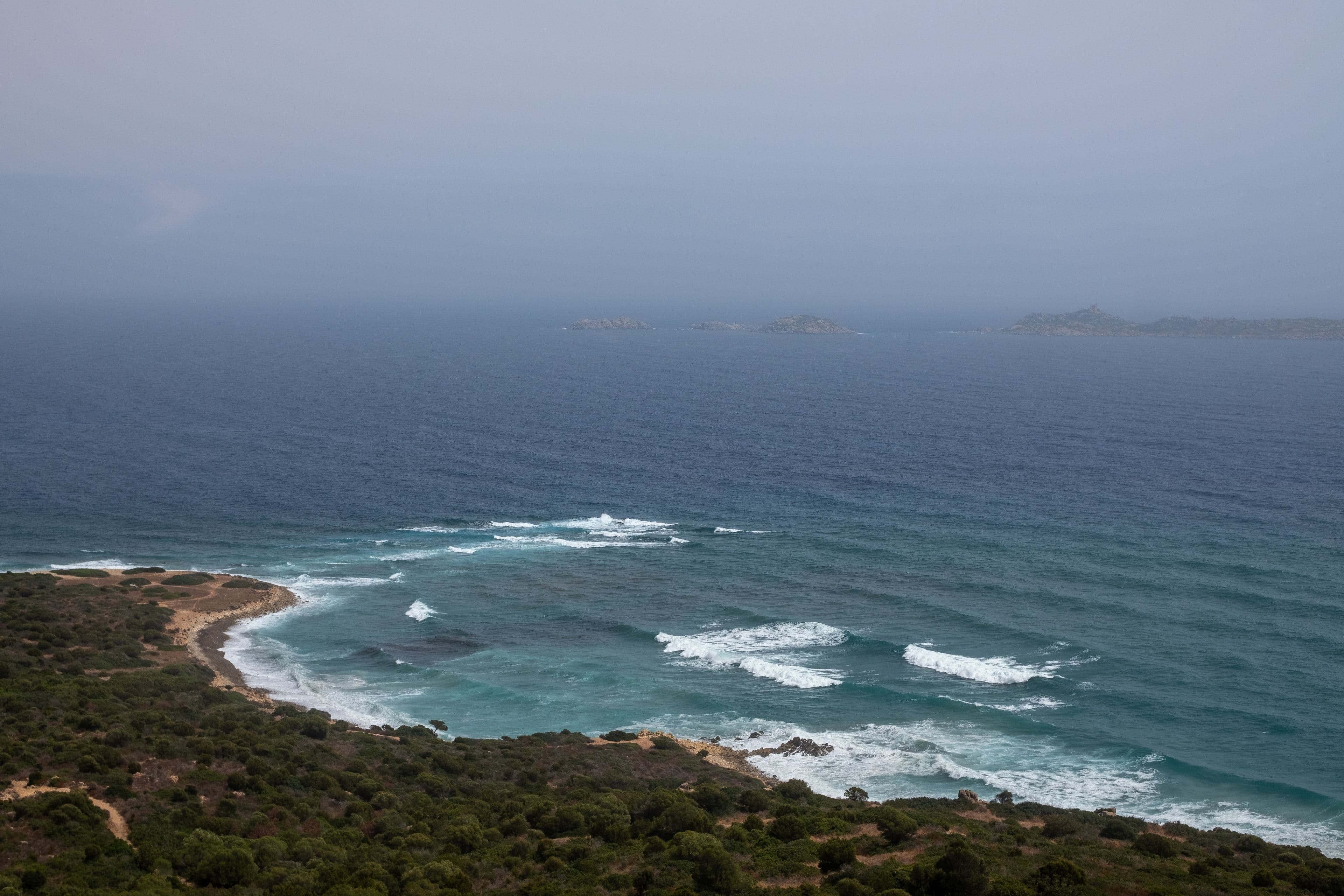 Waves meeting the rugged coastal landscape of Sardinia