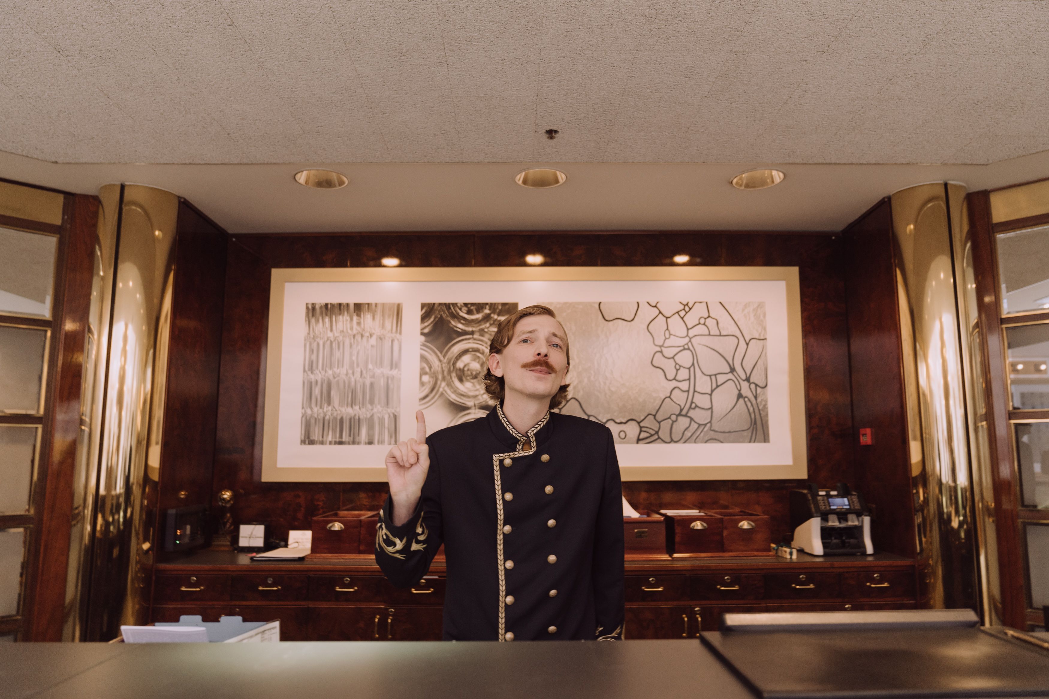 Uniformed concierge behind a warm wood hotel reception desk
