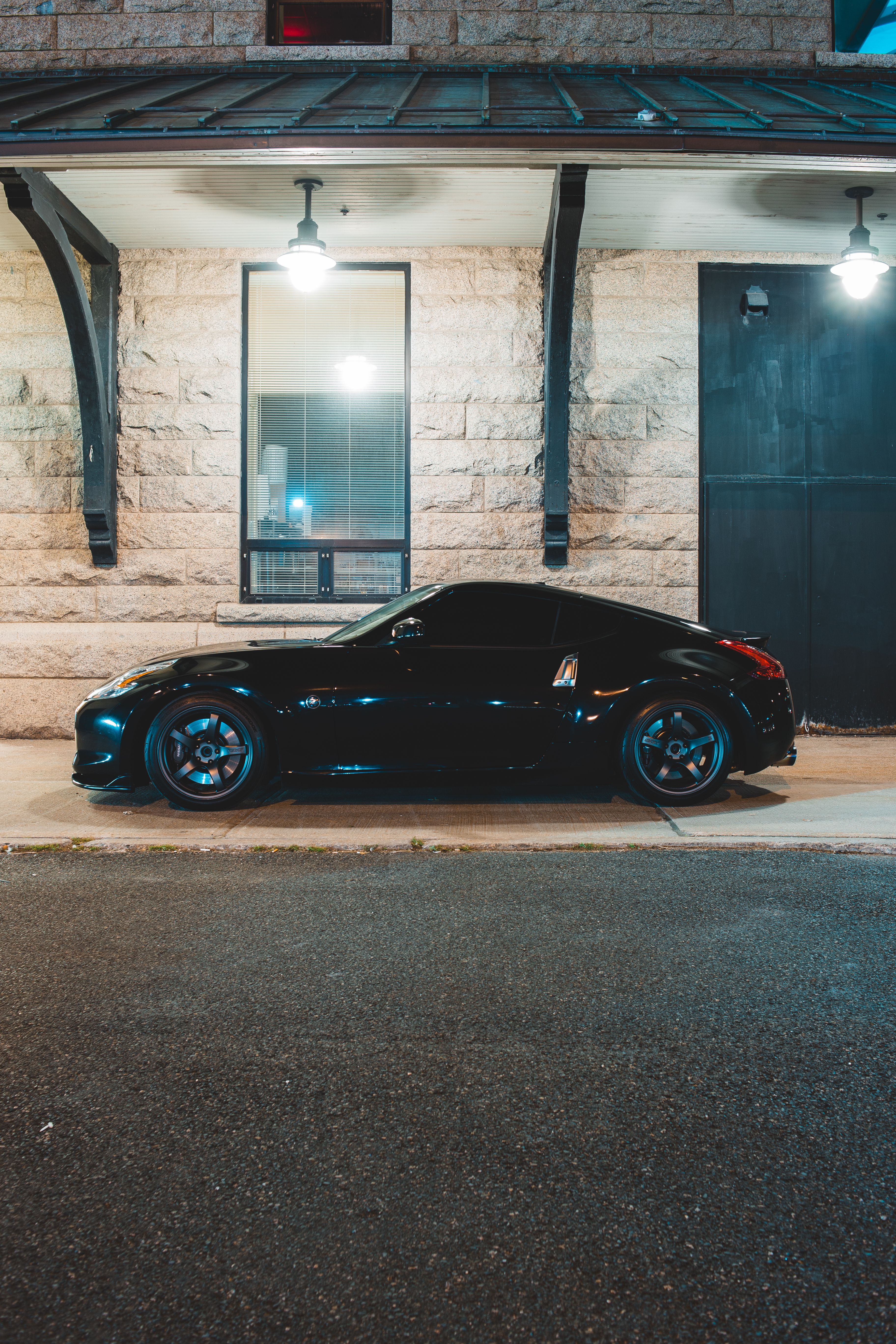 Black sports coupe parked beneath a stone building canopy at night