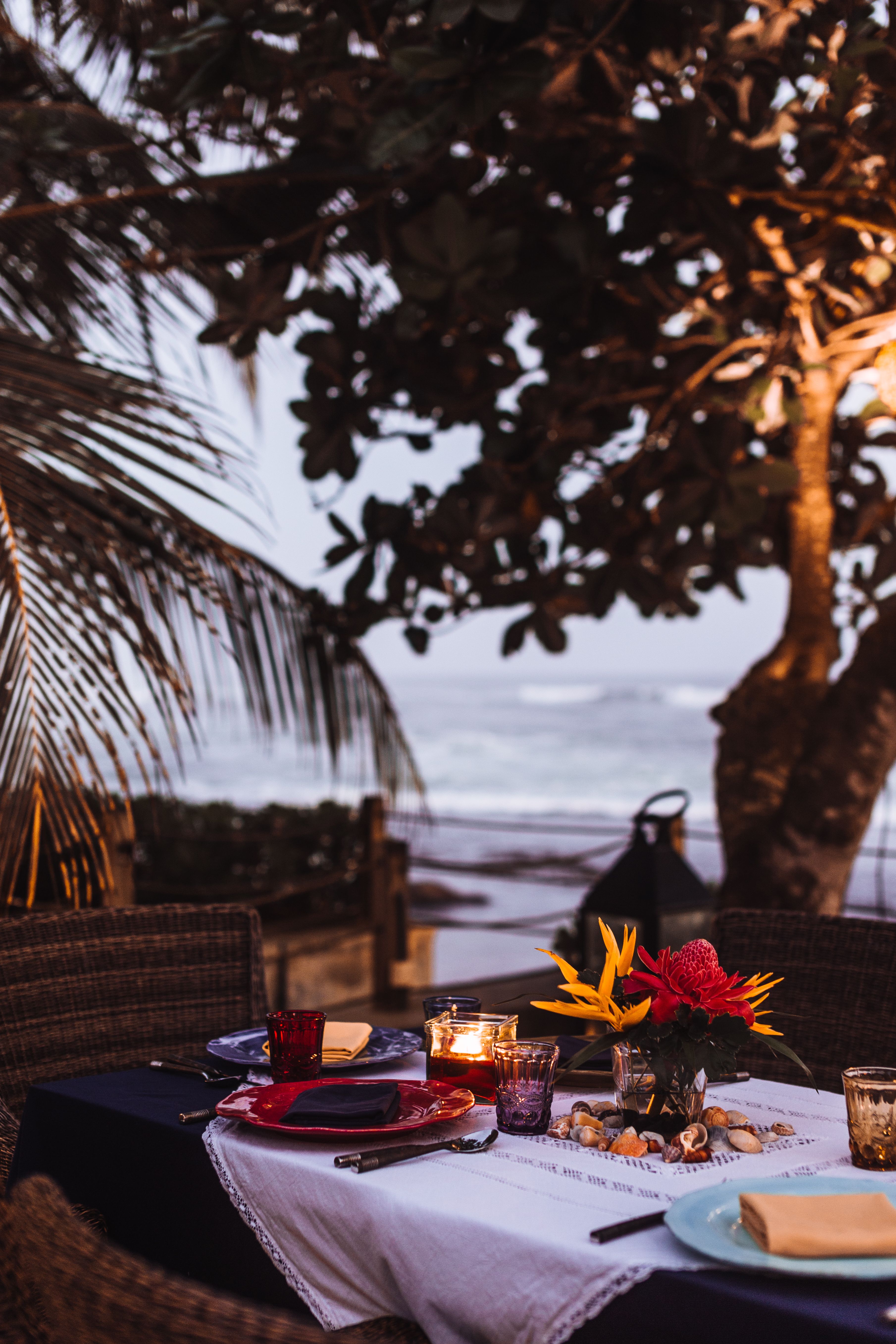 Intimate candlelit table beside the sea at dusk