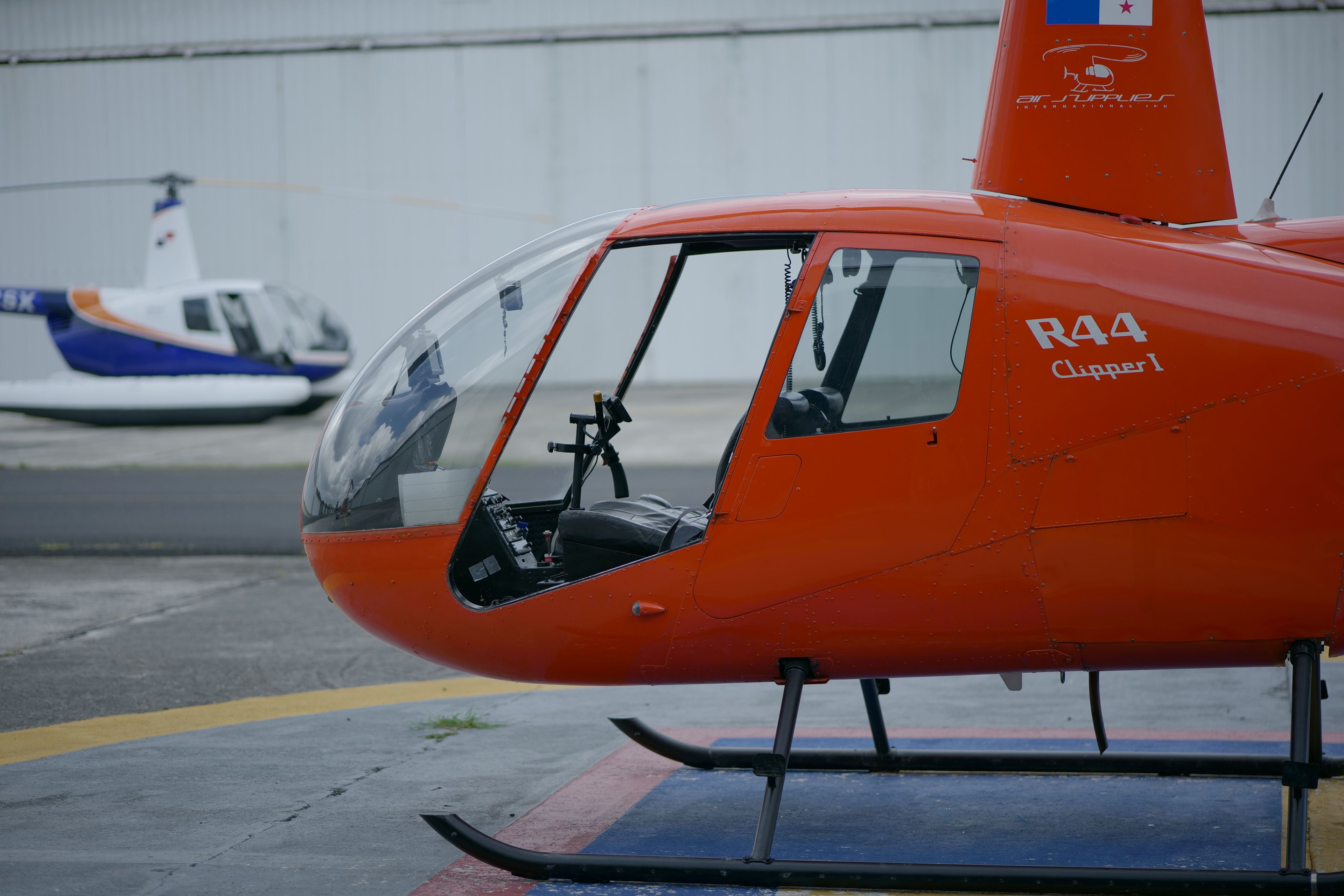 Orange passenger helicopter parked on an airport apron