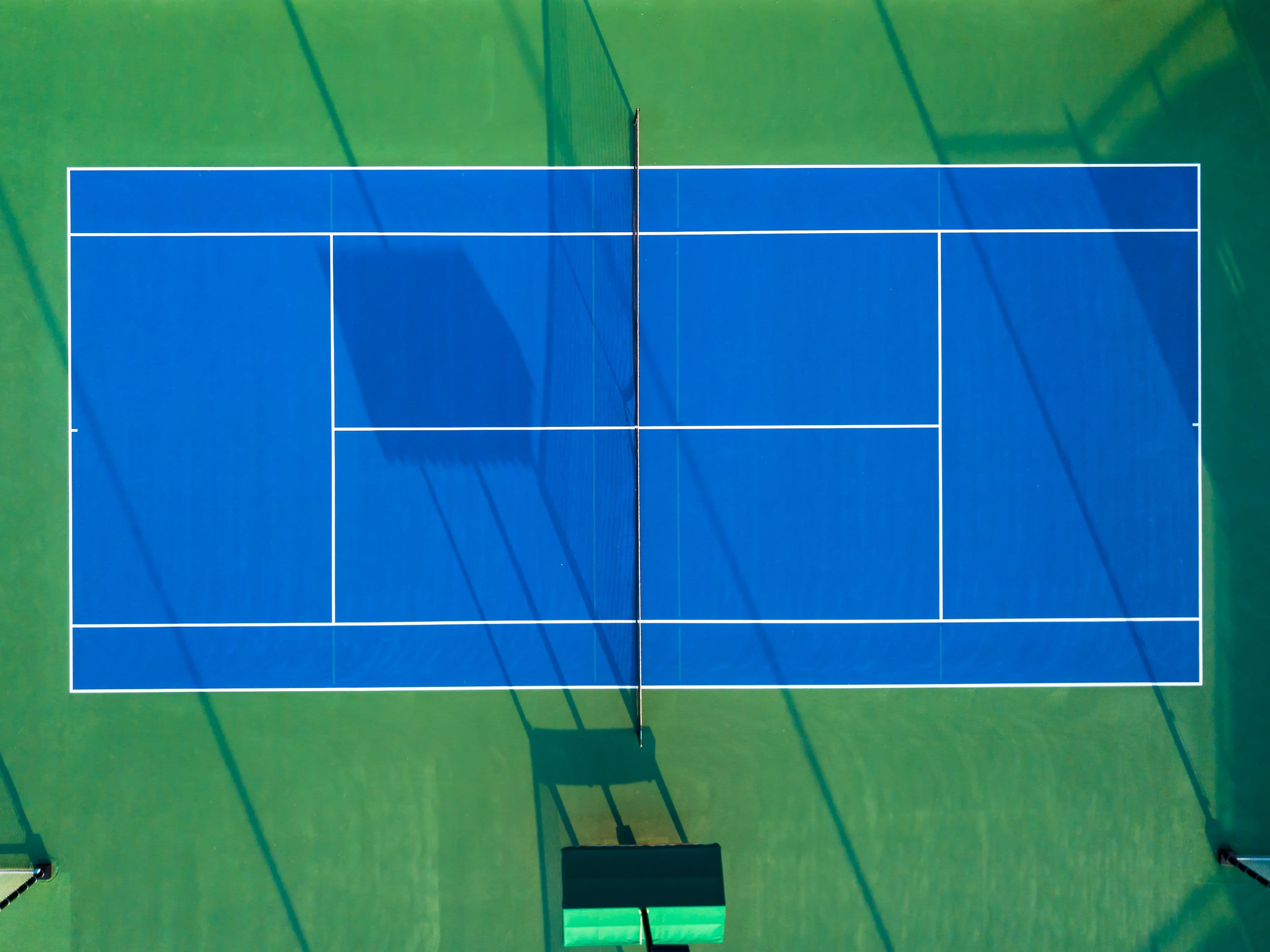 Blue tennis court framed by a green playing surface